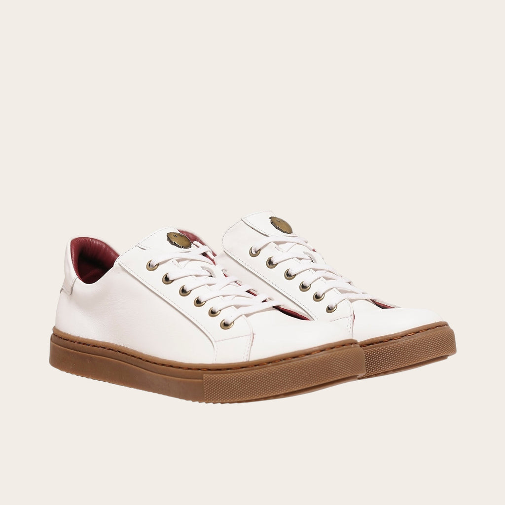 Zapatilla blanca de cuero de vacuno de OLKI con planta de caucho marrón y forro guinda. Diseño clásico con cordones.