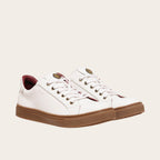 Zapatilla blanca de cuero de vacuno de OLKI con planta de caucho marrón y forro guinda. Diseño clásico con cordones.