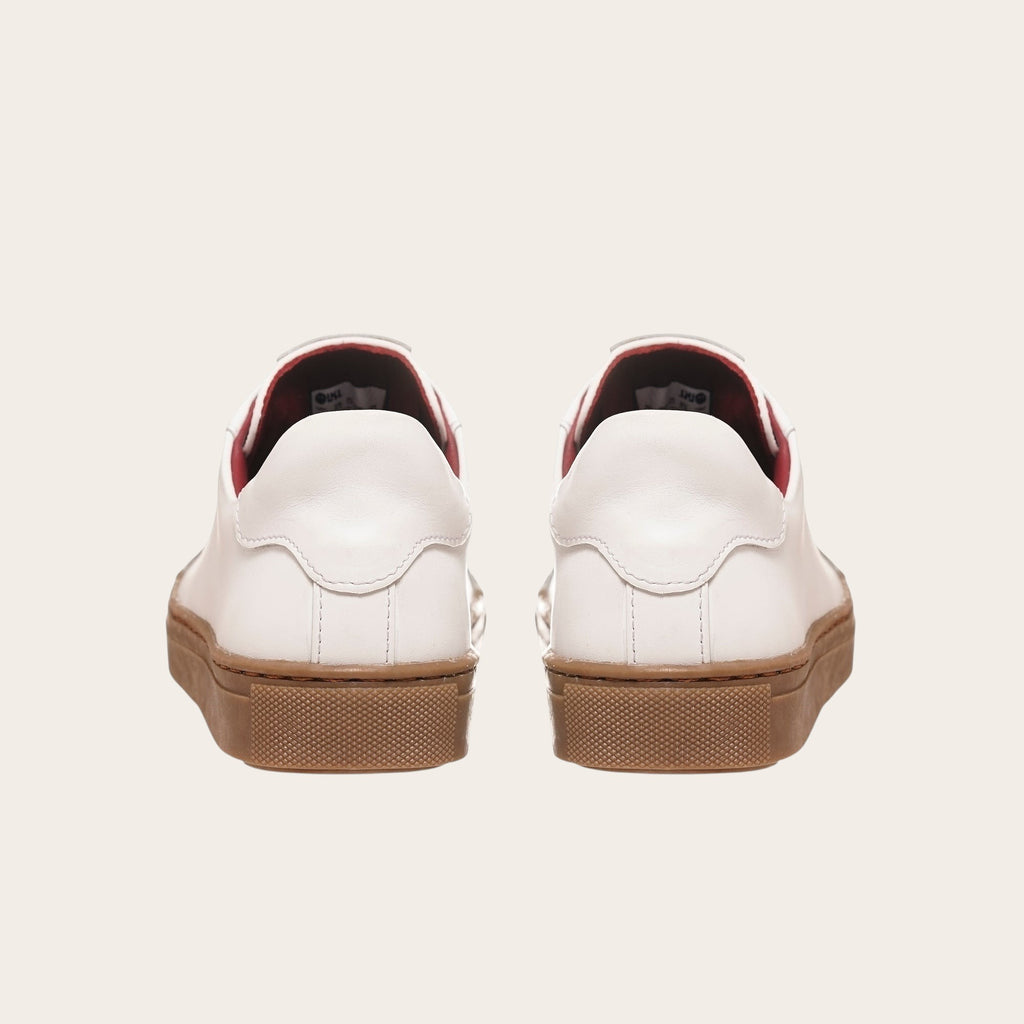 Zapatilla OLKI Tronador blanca de cuero con planta de caucho marrón y forro interior rojo. Diseño clásico.