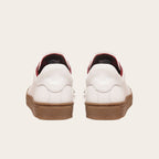 Zapatilla OLKI Tronador blanca de cuero con planta de caucho marrón y forro interior rojo. Diseño clásico.