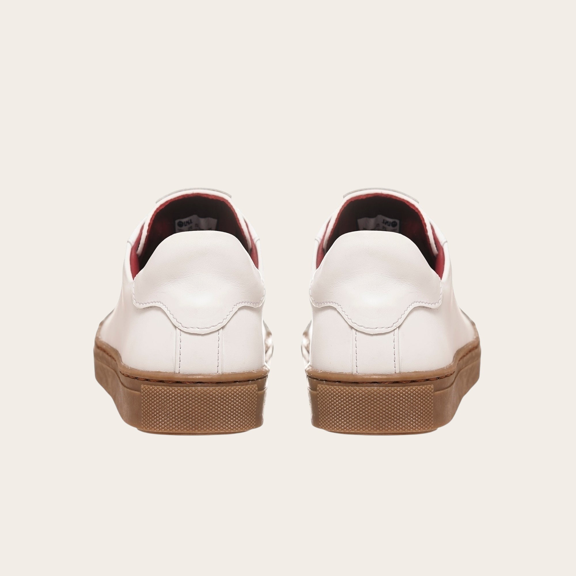 Zapatilla OLKI Tronador blanca de cuero con planta de caucho marrón y forro interior rojo. Diseño clásico.