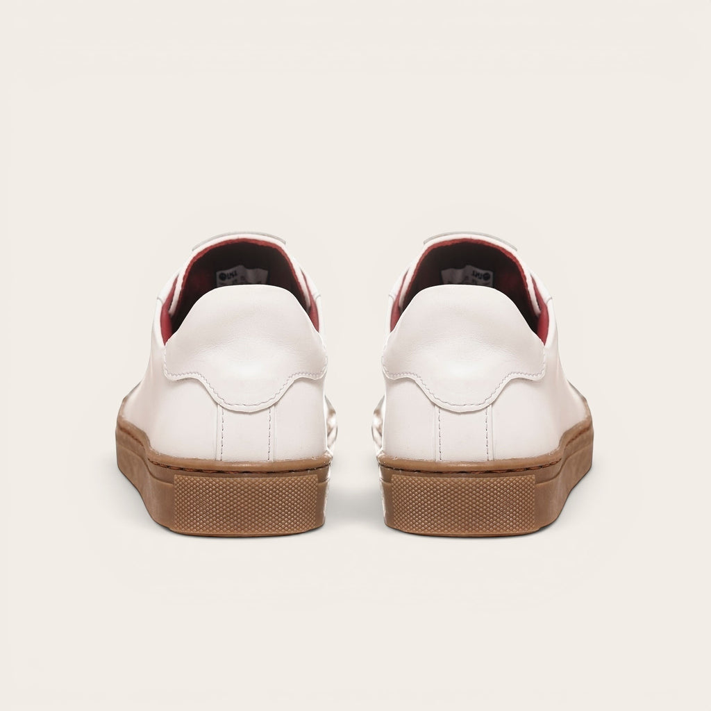 Zapatilla OLKI Tronador blanca de cuero con planta de caucho marrón y forro interior rojo. Diseño clásico.