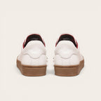 Zapatilla OLKI Tronador blanca de cuero con planta de caucho marrón y forro interior rojo. Diseño clásico.