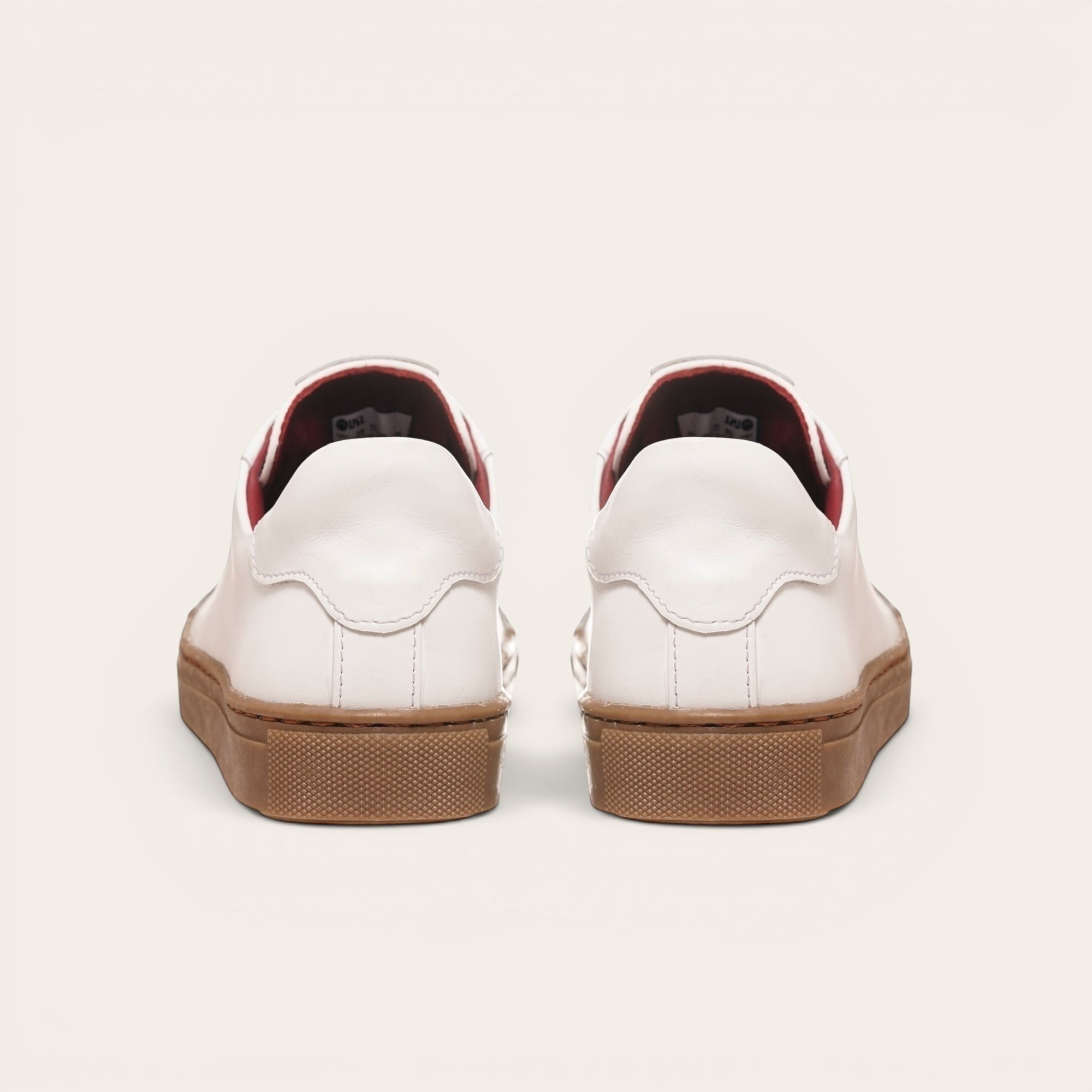 Zapatilla OLKI Tronador blanca de cuero con planta de caucho marrón y forro interior rojo. Diseño clásico.