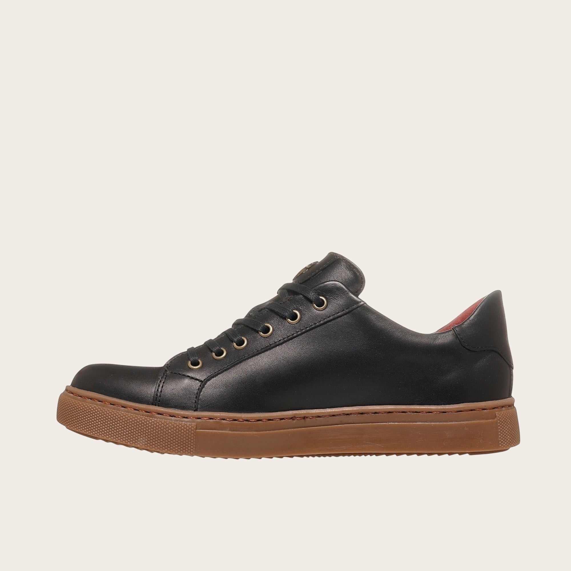 Zapatilla OLKI Tronador negra de cuero de vacuno con suela de caucho marrón y detalle rojo en el talón.