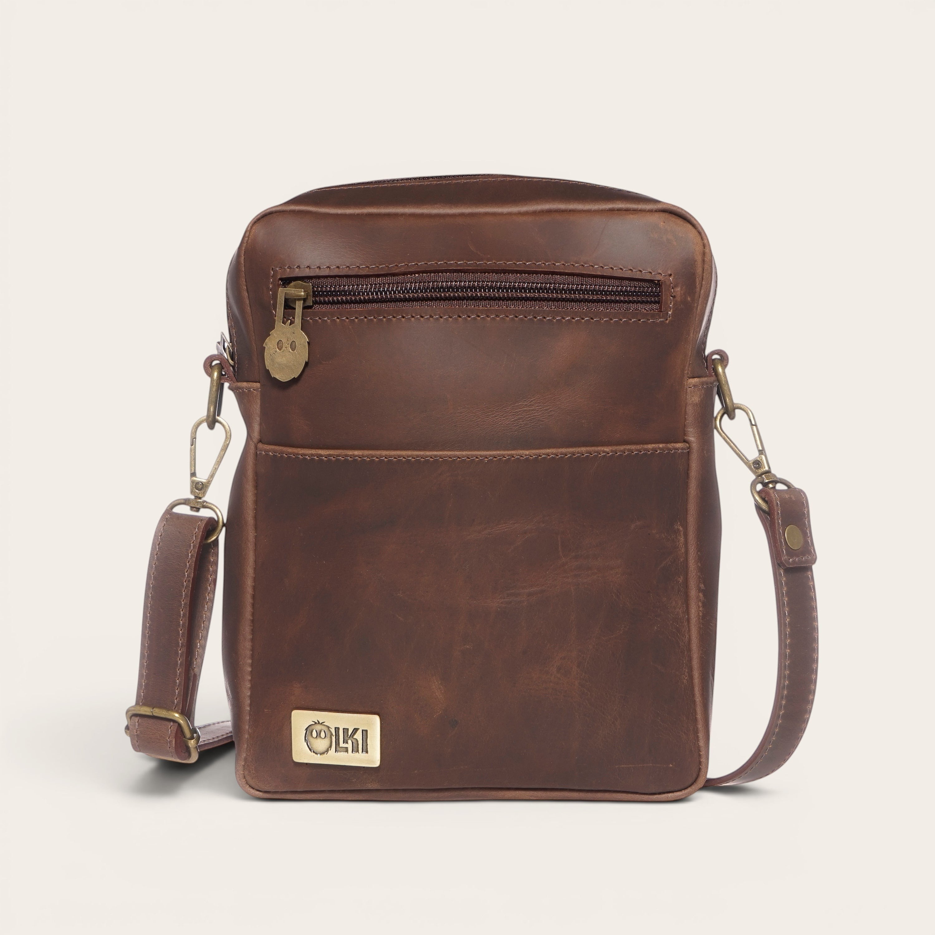 Bandolera Cautín Chocolate de cuero vacuno envejecido de OLKI con bolsillo frontal y correa ajustable.