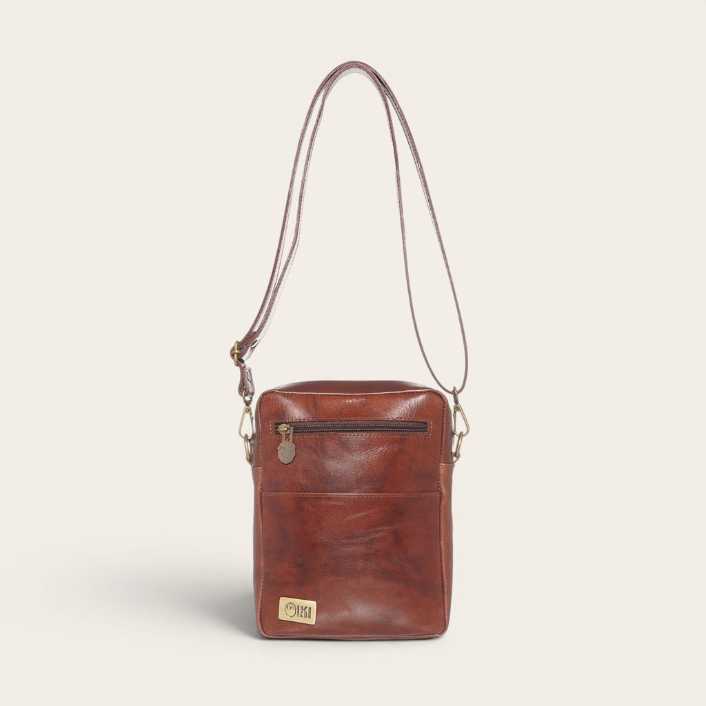 Bandolera Cautín Castaño de piel OLKI con bolsillo frontal y cremallera, ideal para uso diario.
