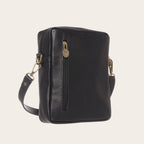 Bandolera negra de cuero natural OLKI con bolsillo exterior con cremallera y herrajes dorados envejecidos.