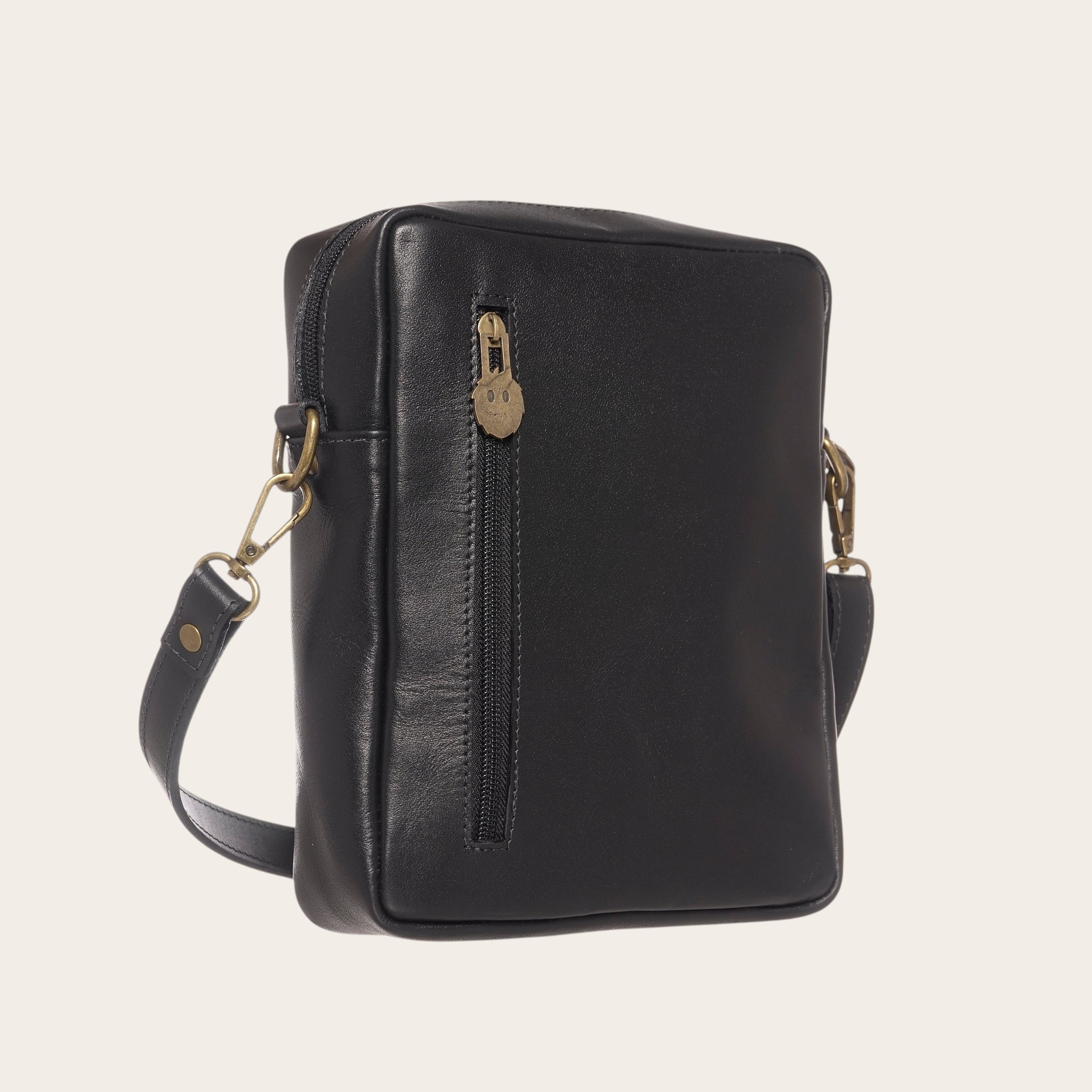 Bandolera negra de cuero natural OLKI con bolsillo exterior con cremallera y herrajes dorados envejecidos.