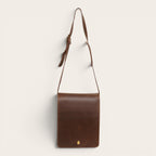 Bandolera de cuero vacuno marrón chocolate OLKI con solapa frontal y cierre dorado con imán. Correa ajustable para hombre.