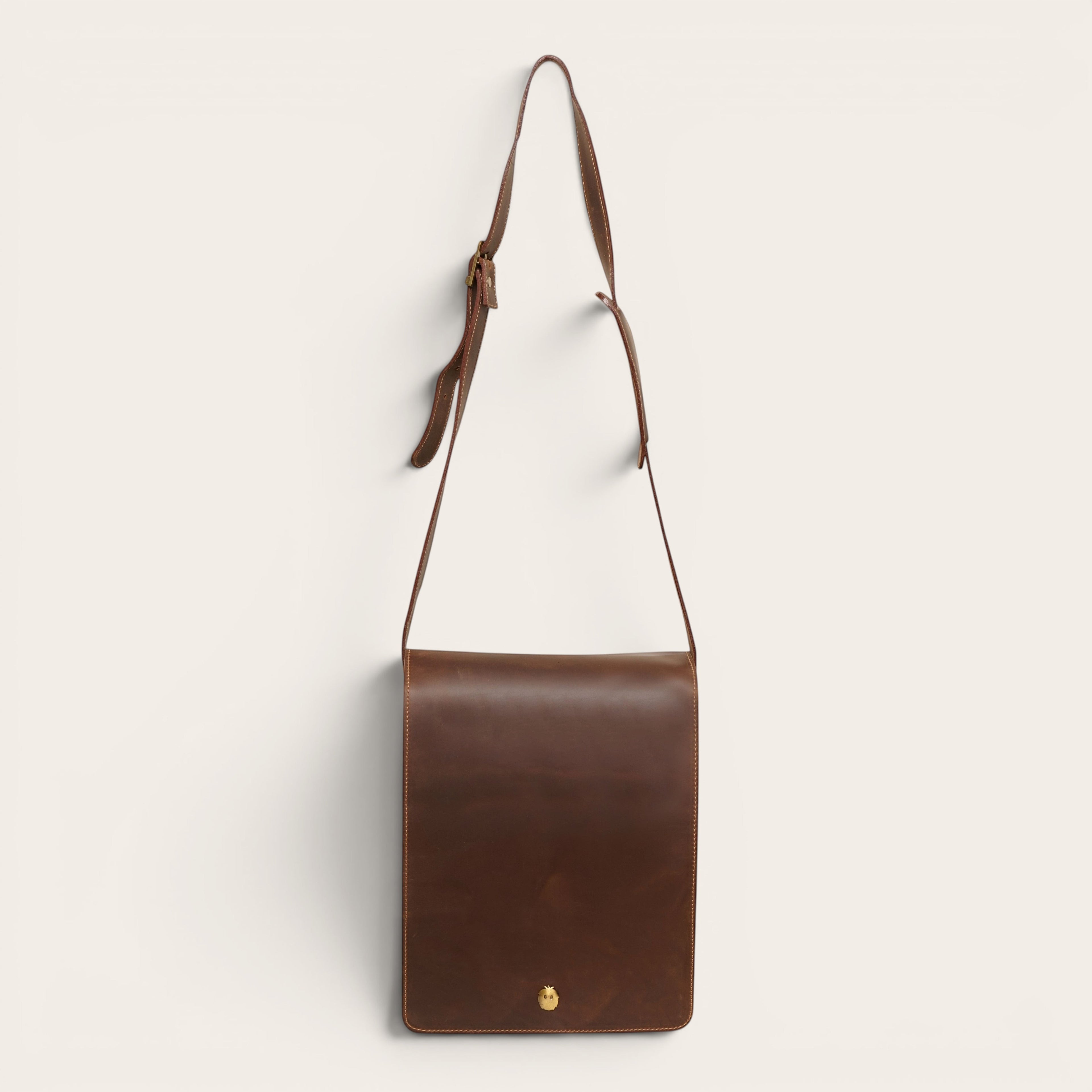 Bandolera de cuero vacuno marrón chocolate OLKI con solapa frontal y cierre dorado con imán. Correa ajustable para hombre.