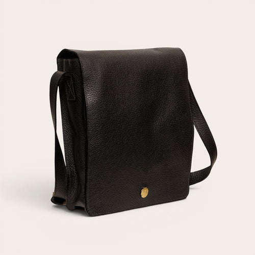 Bandolera negra texturizada de cuero OLKI con solapa y detalle metálico dorado. Correa ajustable para llevar cruzada o al hombro.