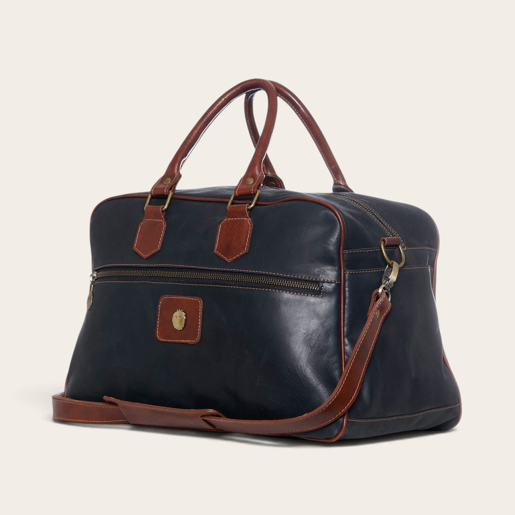 Bolso de viaje OLKI Rahue en cuero natural negro con detalles en cuero café, asas reforzadas y correa ajustable.
