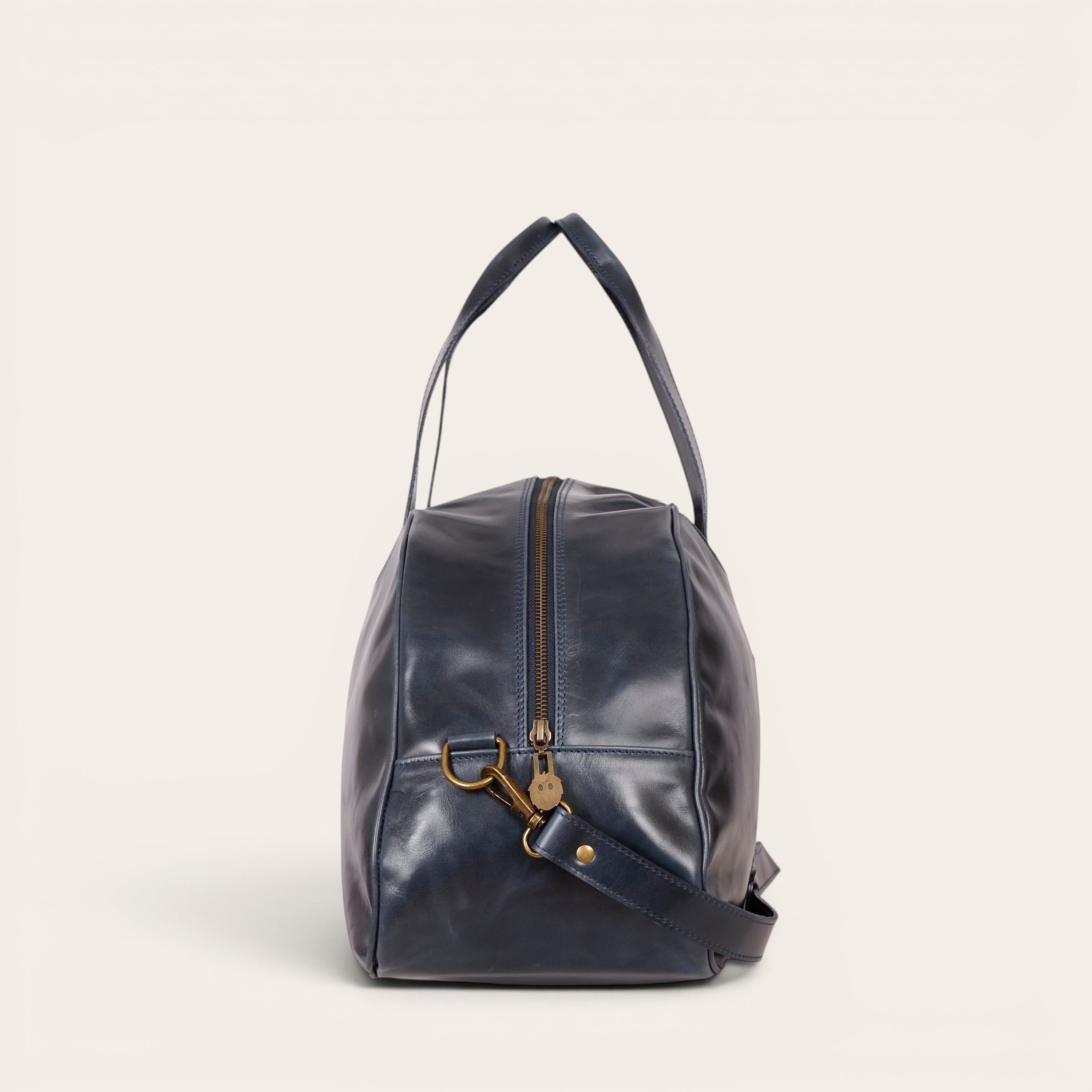 Bolso de viaje OLKI Baker azul marino de cuero con cremallera metálica y asas superiores.