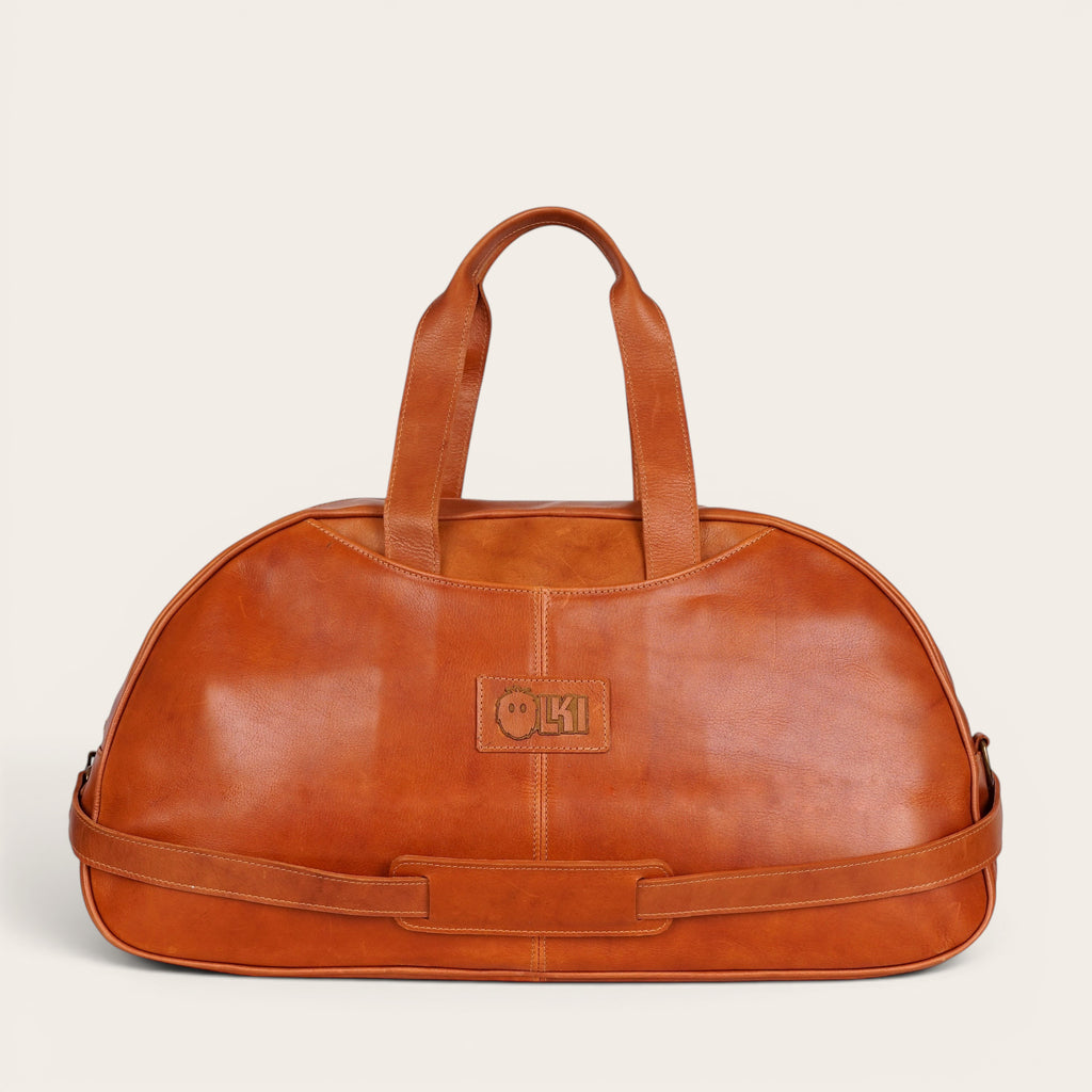 Bolso de viaje Baker Curry de cuero natural de vacuno de OLKI con asas y correa ajustable. Bolsillos interiores y exteriores, costuras reforzadas y herrajes envejecidos.
