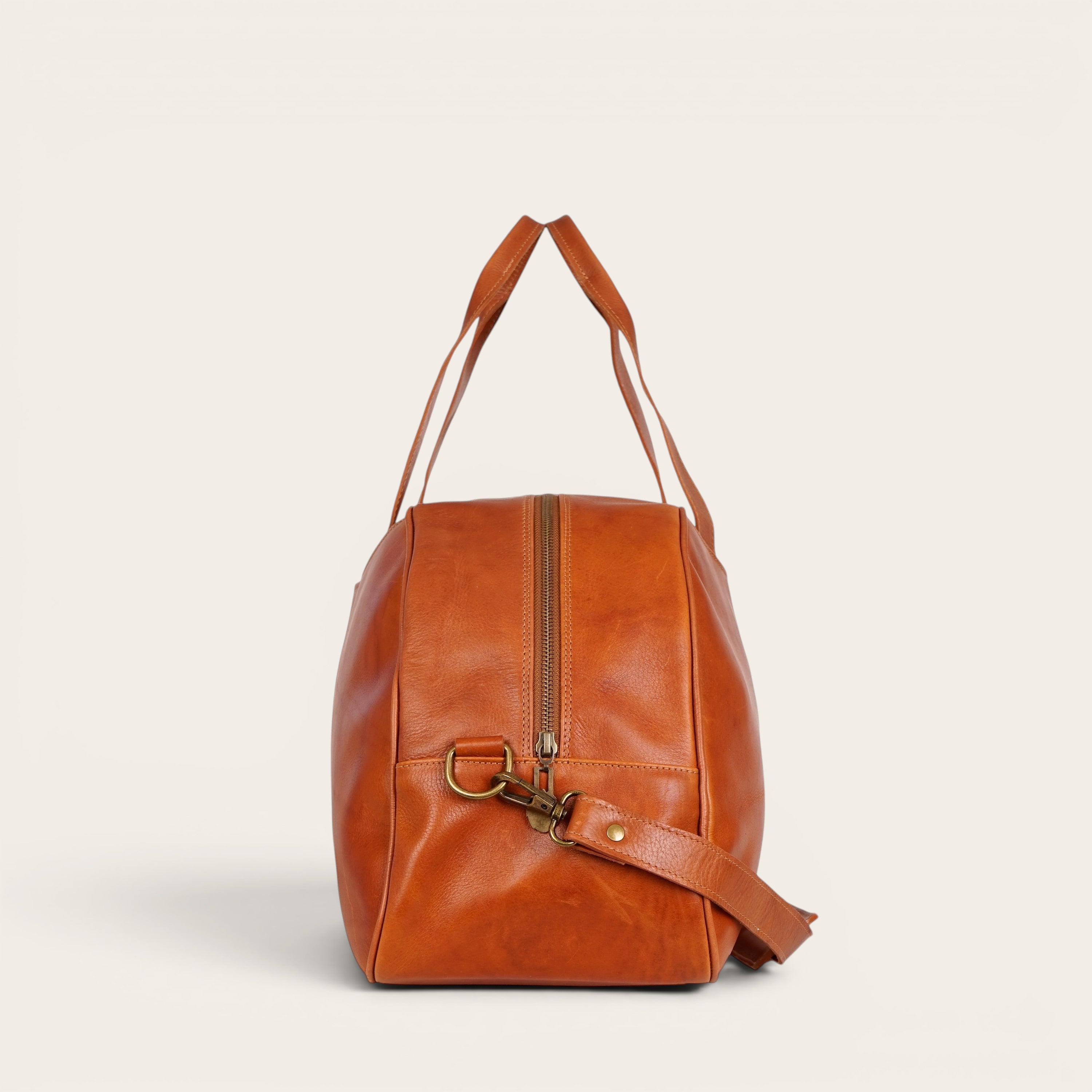 Bolso de viaje Baker Curry de cuero natural de vacuno de OLKI con asas y correa ajustable. Bolsillos interiores y exteriores, costuras reforzadas y herrajes envejecidos.