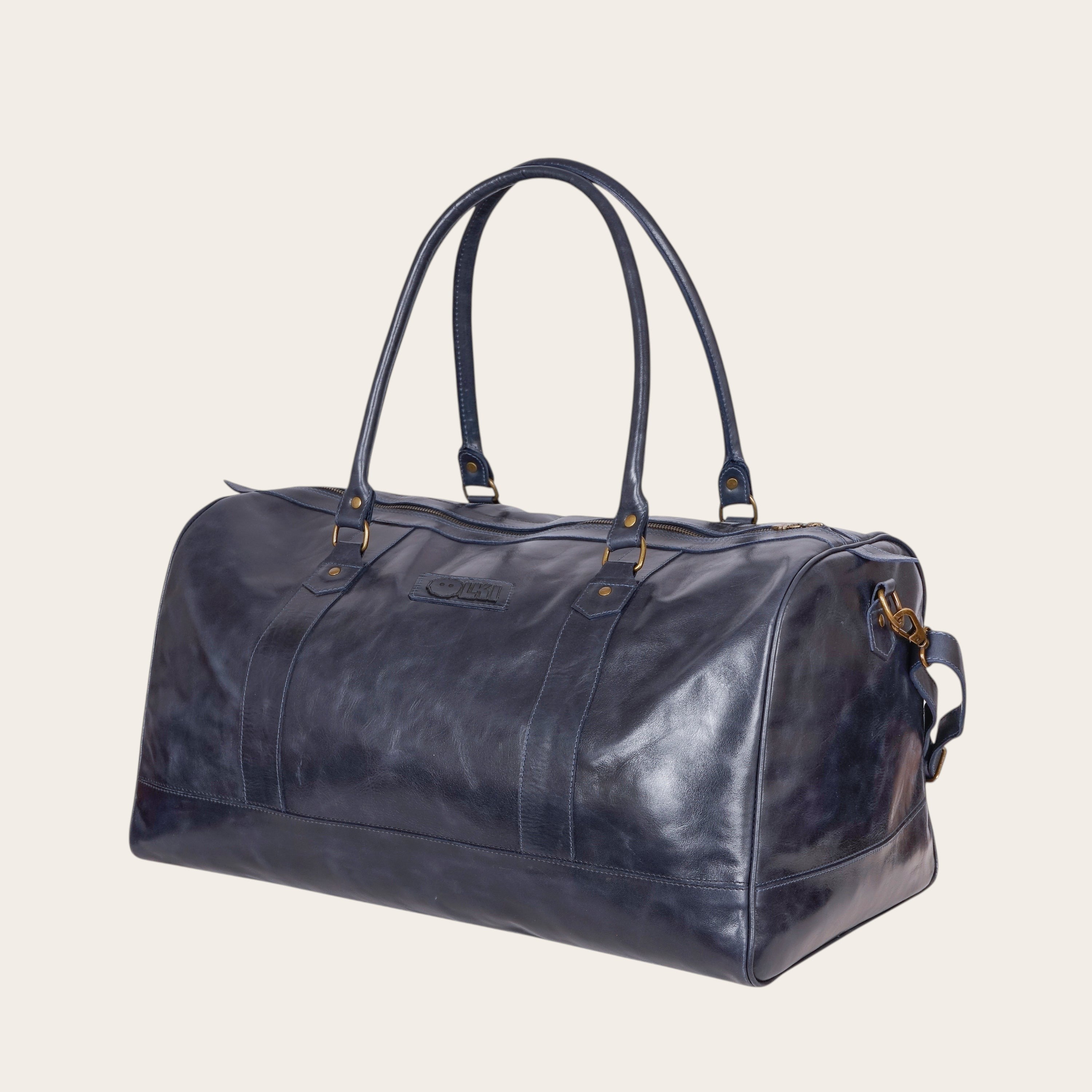 Bolso de viaje OLKI Futaleufu azul marino de cuero desgastado con asas superiores y correa de hombro.