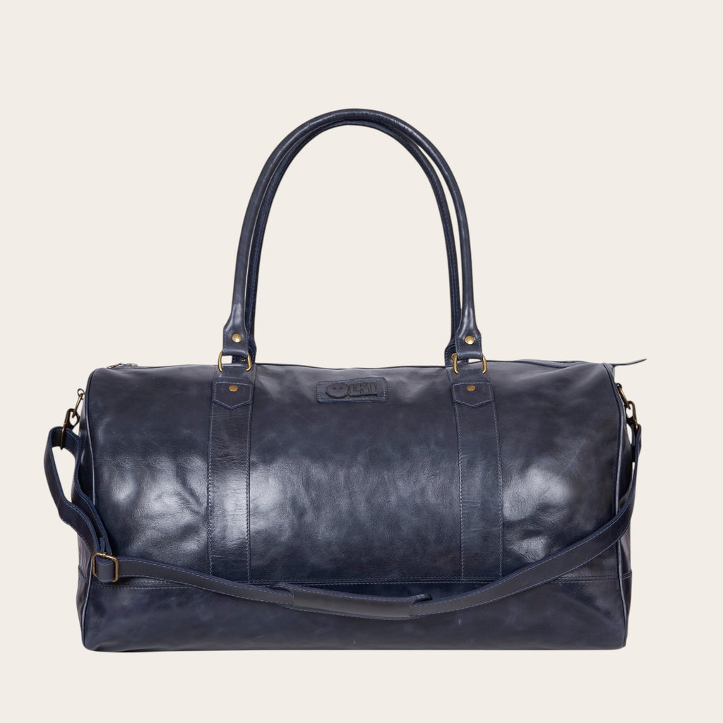 Bolso de viaje OLKI Futaleufu azul marino de cuero desgastado con asas superiores y correa de hombro ajustable.
