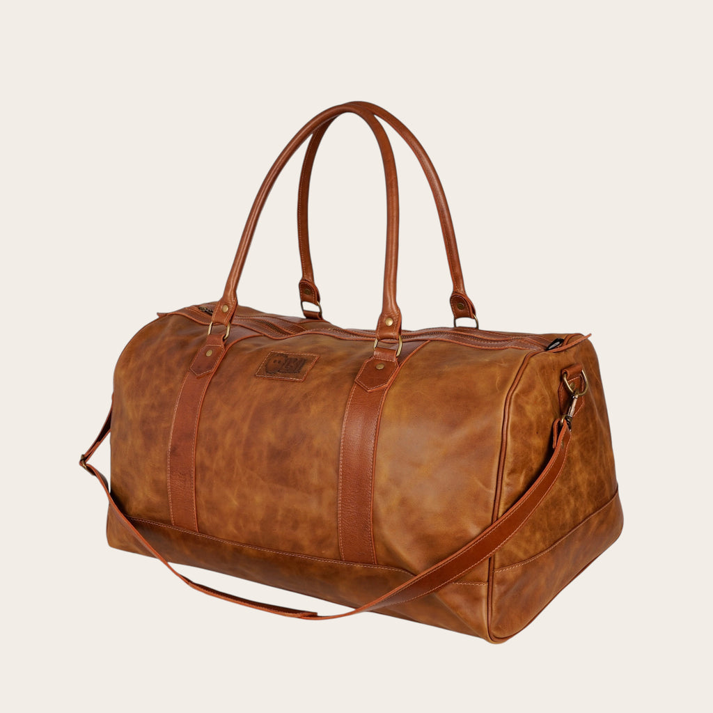 Bolso de viaje OLKI Futaleufu Carmelo Combinado de cuero genuino color caramel con correa ajustable y asas superiores.