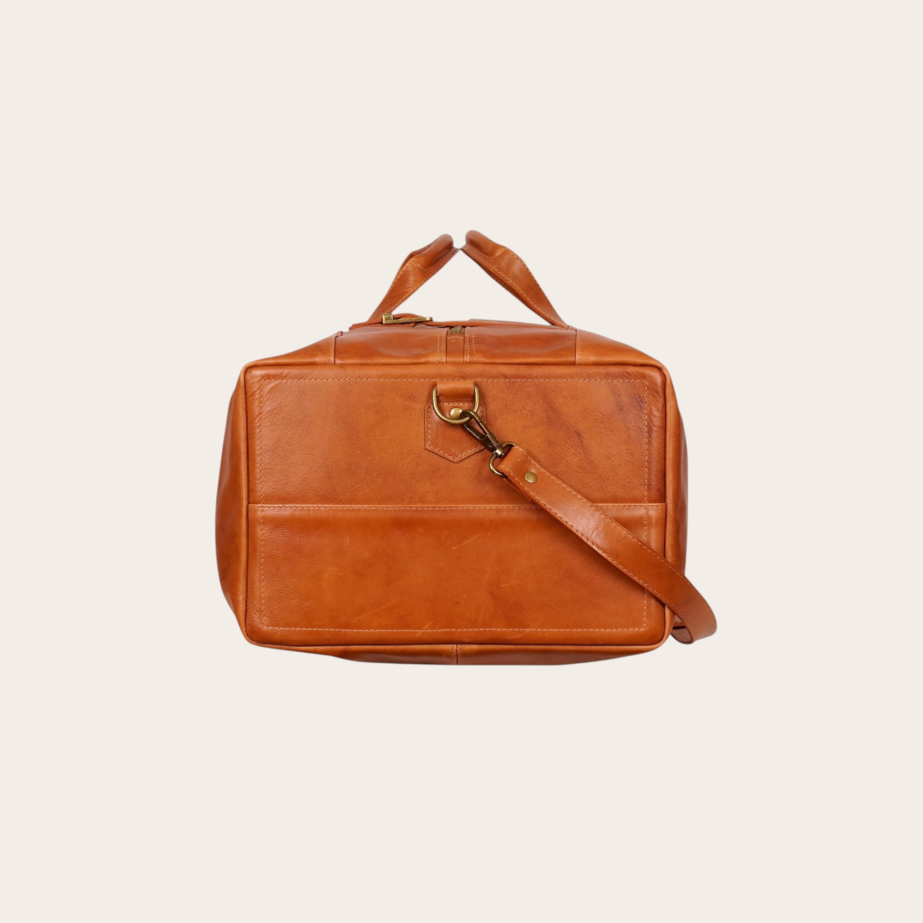 Bolso de viaje OLKI Yelcho en cuero color curry con asas y correa ajustable para el hombro.