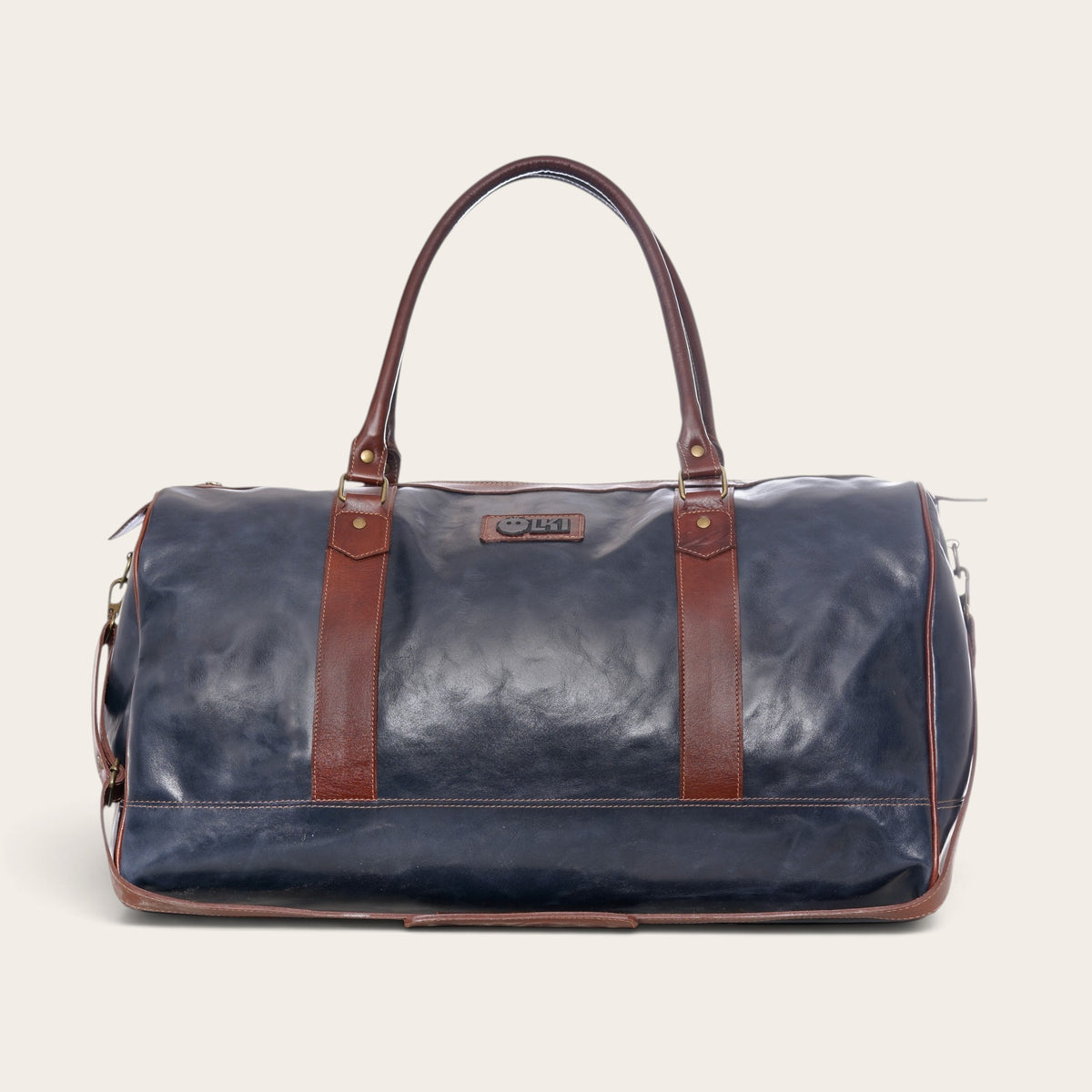 Bolso de viaje OLKI Futaleufu en cuero azul con detalles en cuero marrón, estilo duffel bag con costuras reforzadas.