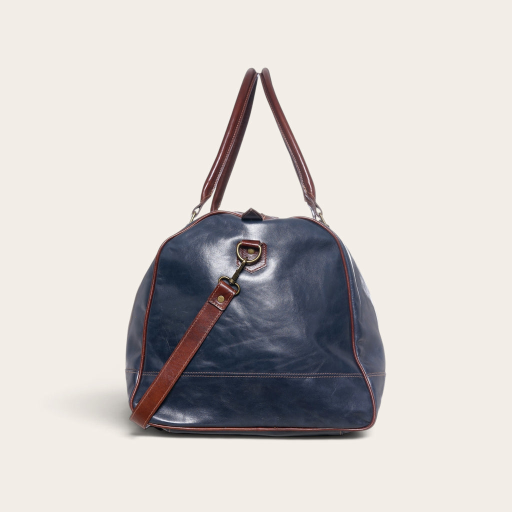 Bolso de viaje OLKI Futaleufu en cuero azul con detalles y correas en cuero marrón, diseño tipo duffel bag.