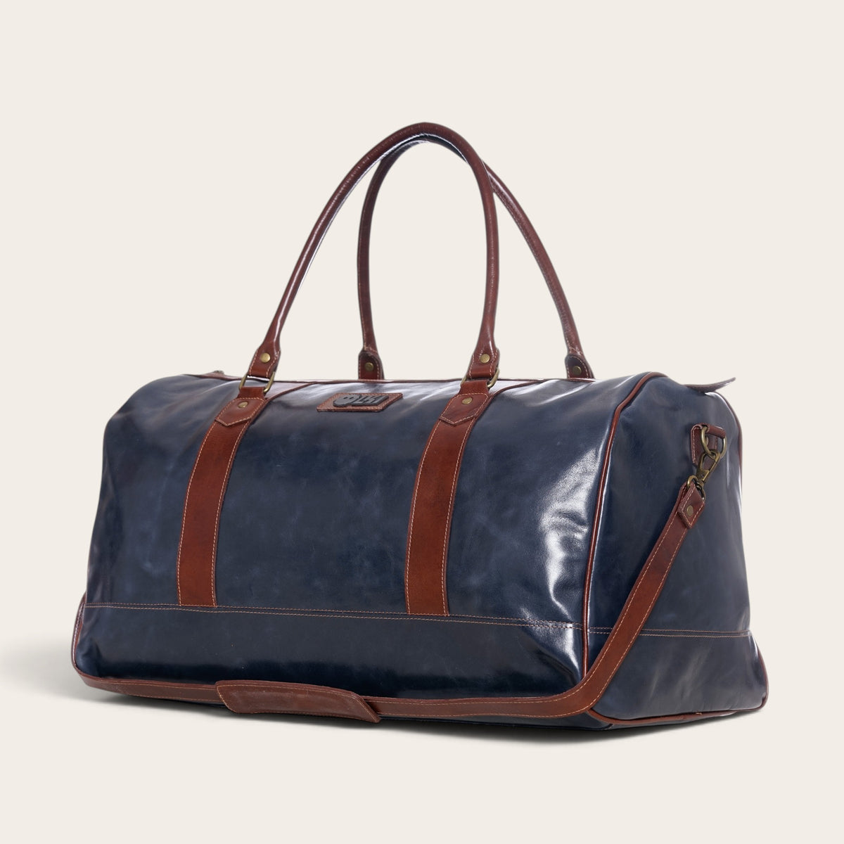 Bolso de viaje OLKI Futaleufu en cuero azul con detalles y correas en cuero marrón, diseño tipo duffel bag elegante.