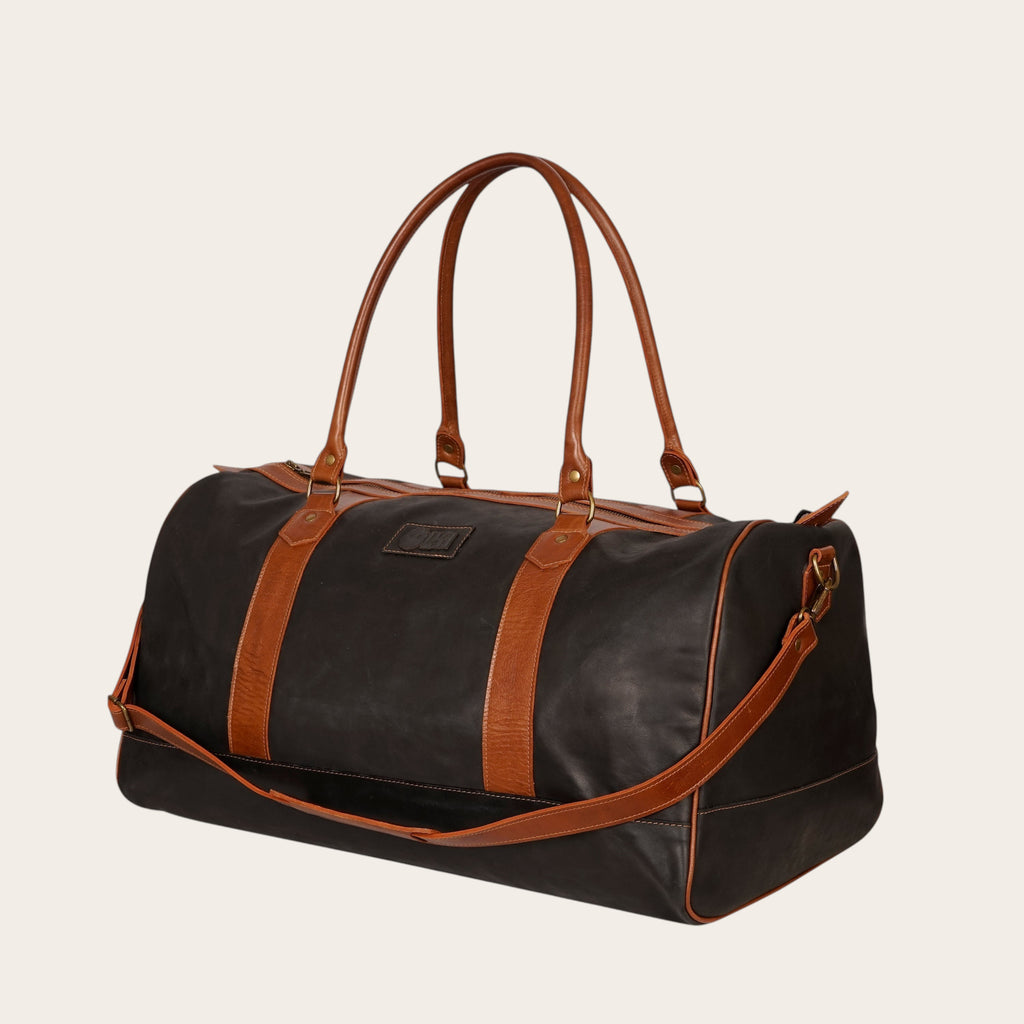 Bolso de viaje OLKI Futaleufu negro de cuero de vacuno con detalles en cuero marrón y herrajes envejecidos.