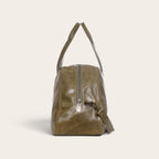 Bolso de viaje OLKI Baker en cuero verde oliva con asas superiores y correa ajustable, vista lateral