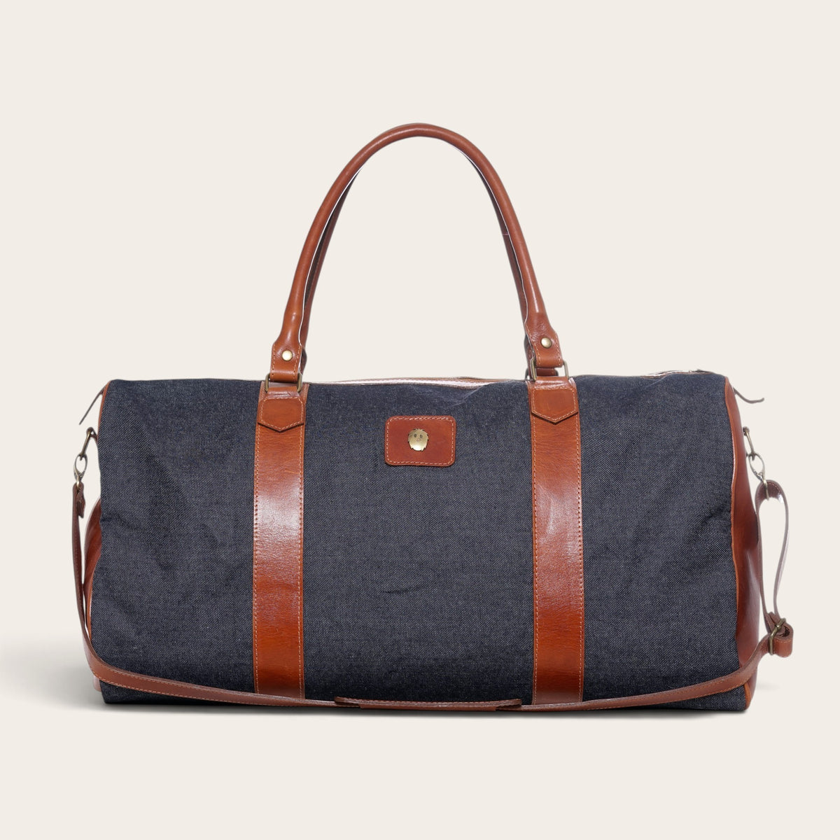 Bolso de viaje OLKI Futaleufú azul de mezclilla con detalles en cuero marrón y asas resistentes para escapadas.