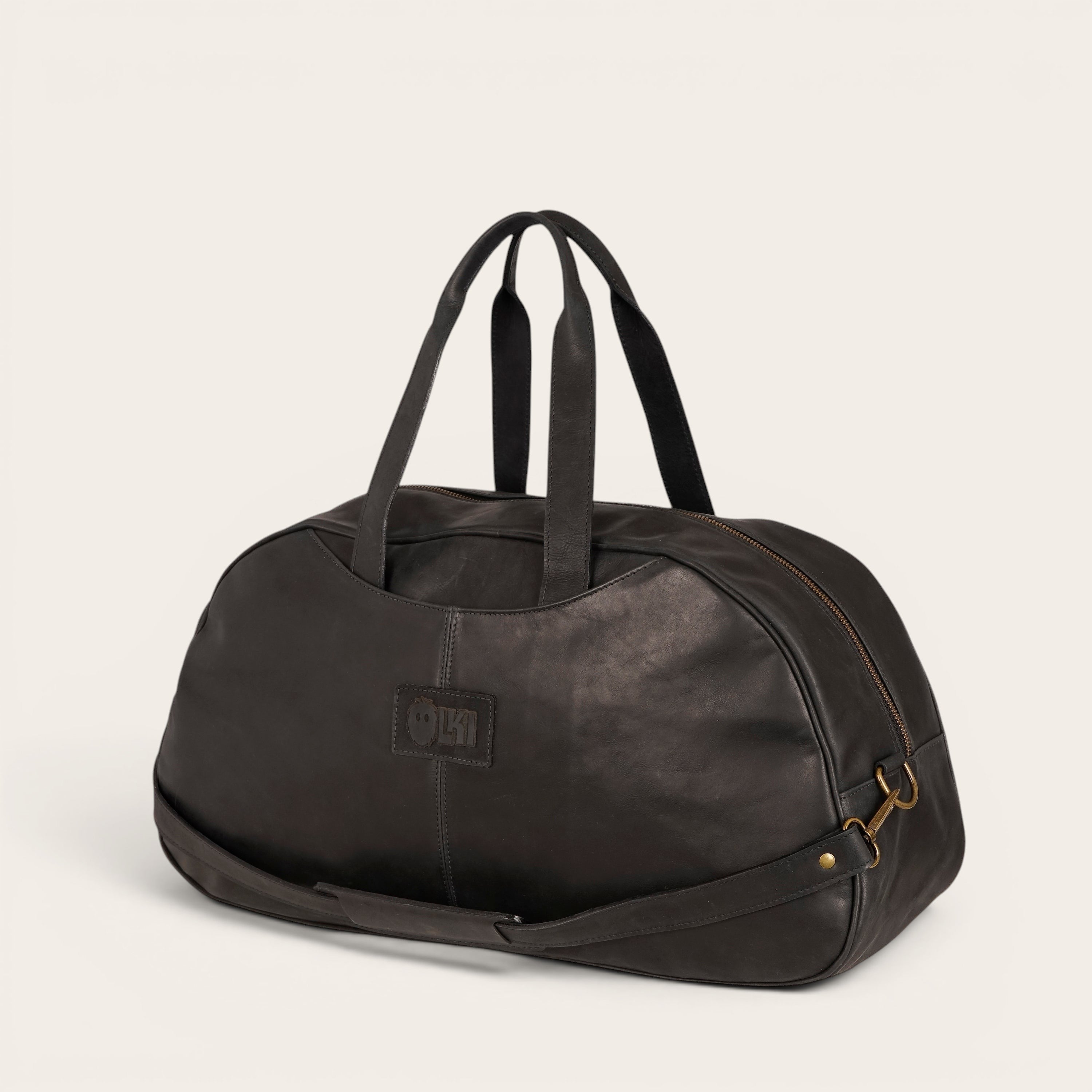 Bolso de viaje Baker negro de cuero de OLKI con asas superiores y correa de hombro desmontable.
