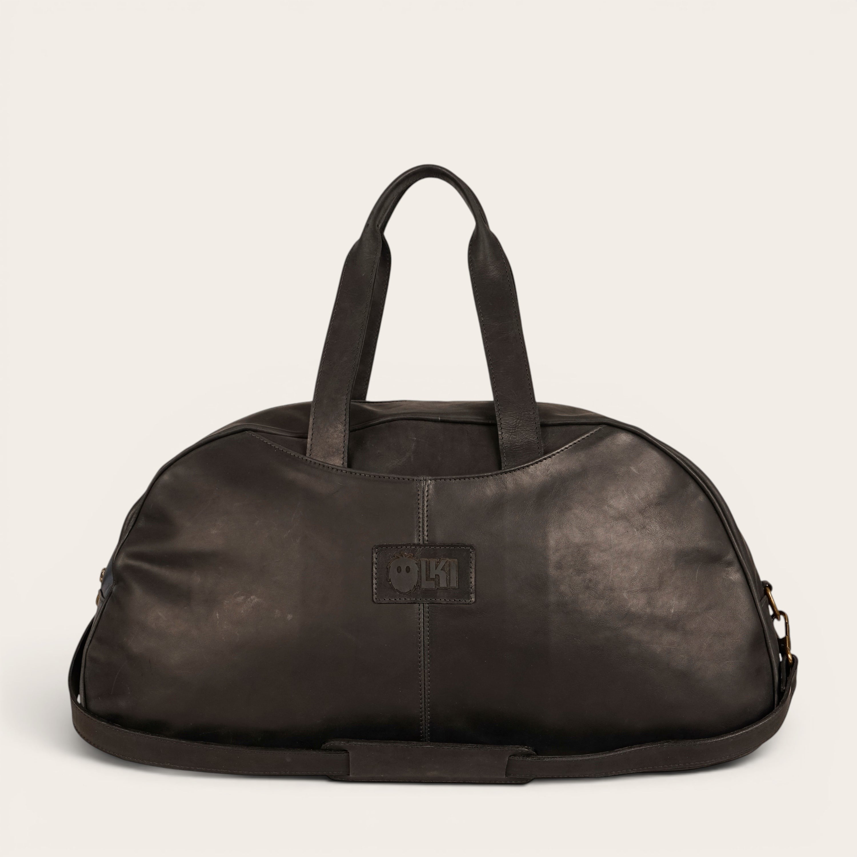 Bolso de viaje Baker negro de cuero de OLKI con asas superiores y correa de hombro desmontable.