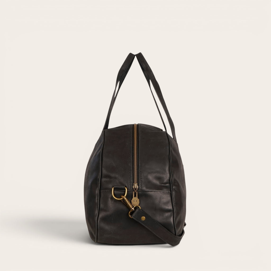 Bolso de viaje Baker negro de cuero de OLKI con asas superiores y correa de hombro desmontable.