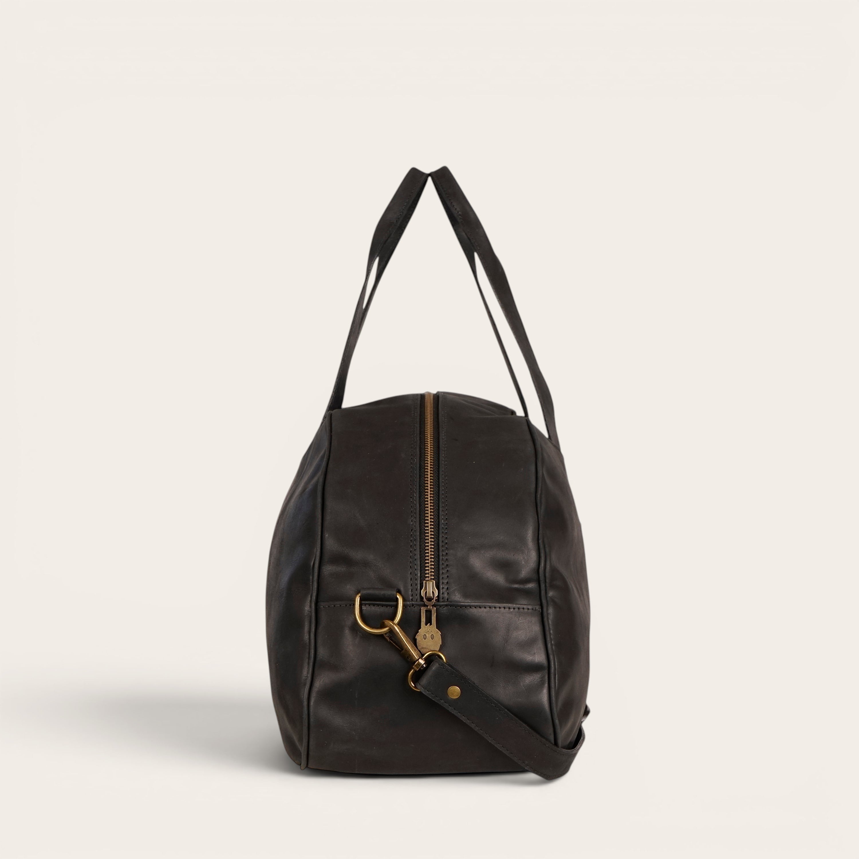 Bolso de viaje Baker negro de cuero de OLKI con asas superiores y correa de hombro desmontable.