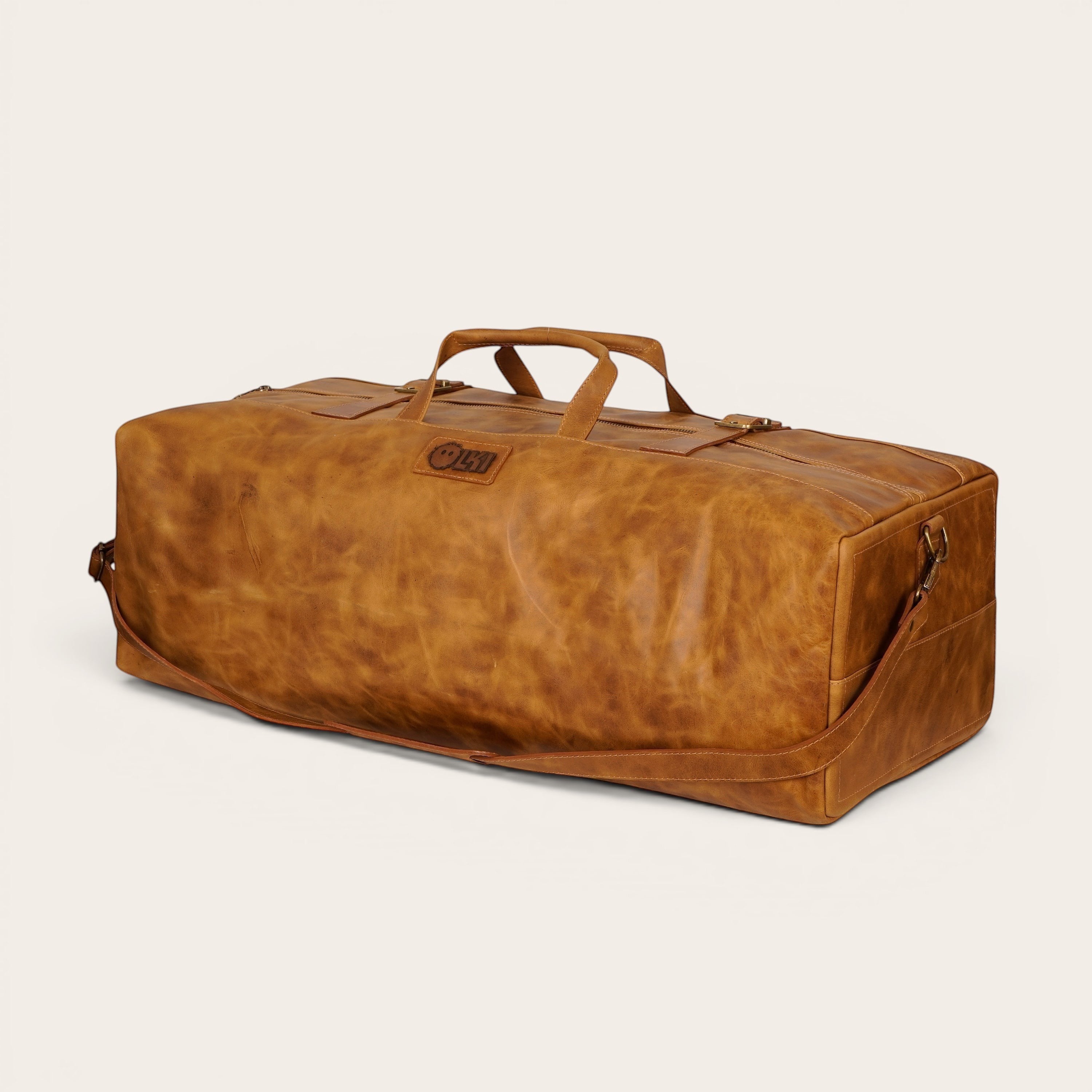 Bolso de fin de semana OLKI Yelcho en cuero color caramelo con asas superiores y correa de hombro ajustable.