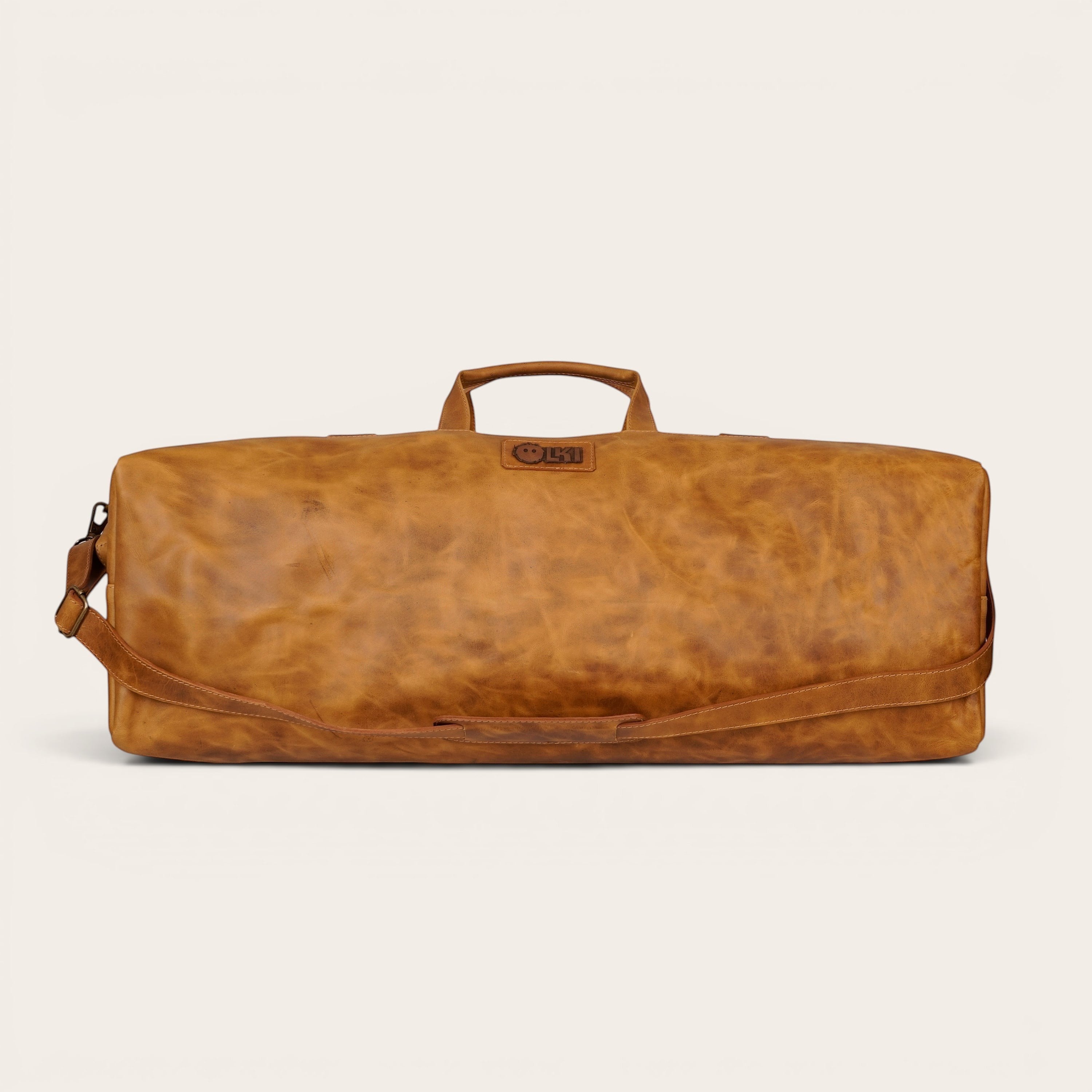 Bolso de fin de semana OLKI Yelcho en cuero color caramelo con asas superiores y correa de hombro ajustable.