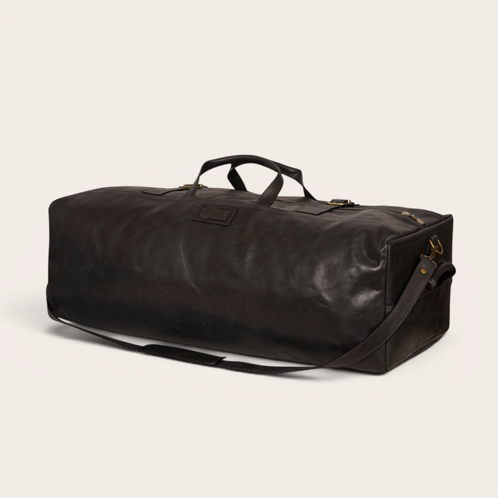 Bolso de viaje OLKI Yelcho negro de piel con asas y correa de hombro, ideal para escapadas.