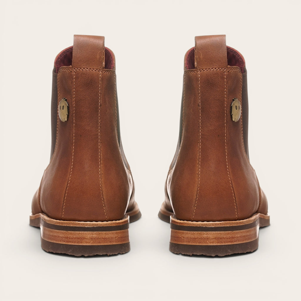 Botín Chelsea de cuero moka para hombre OLKI con suela de caucho chocolate y elásticos laterales. Detalle de lengüeta trasera.