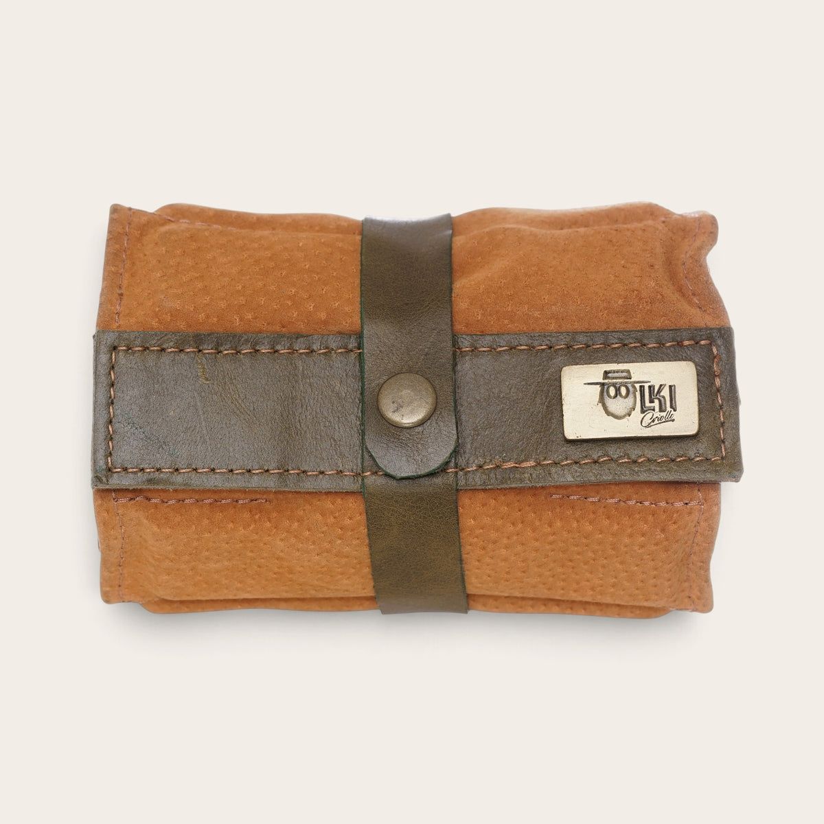 Estuche enrollable para dominós OLKI de cuero natural color café con cierre de correa y placa metálica de la marca
