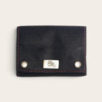 Estuche para naipes OLKI de cuero natural negro con costuras rojas y placa metálica frontal