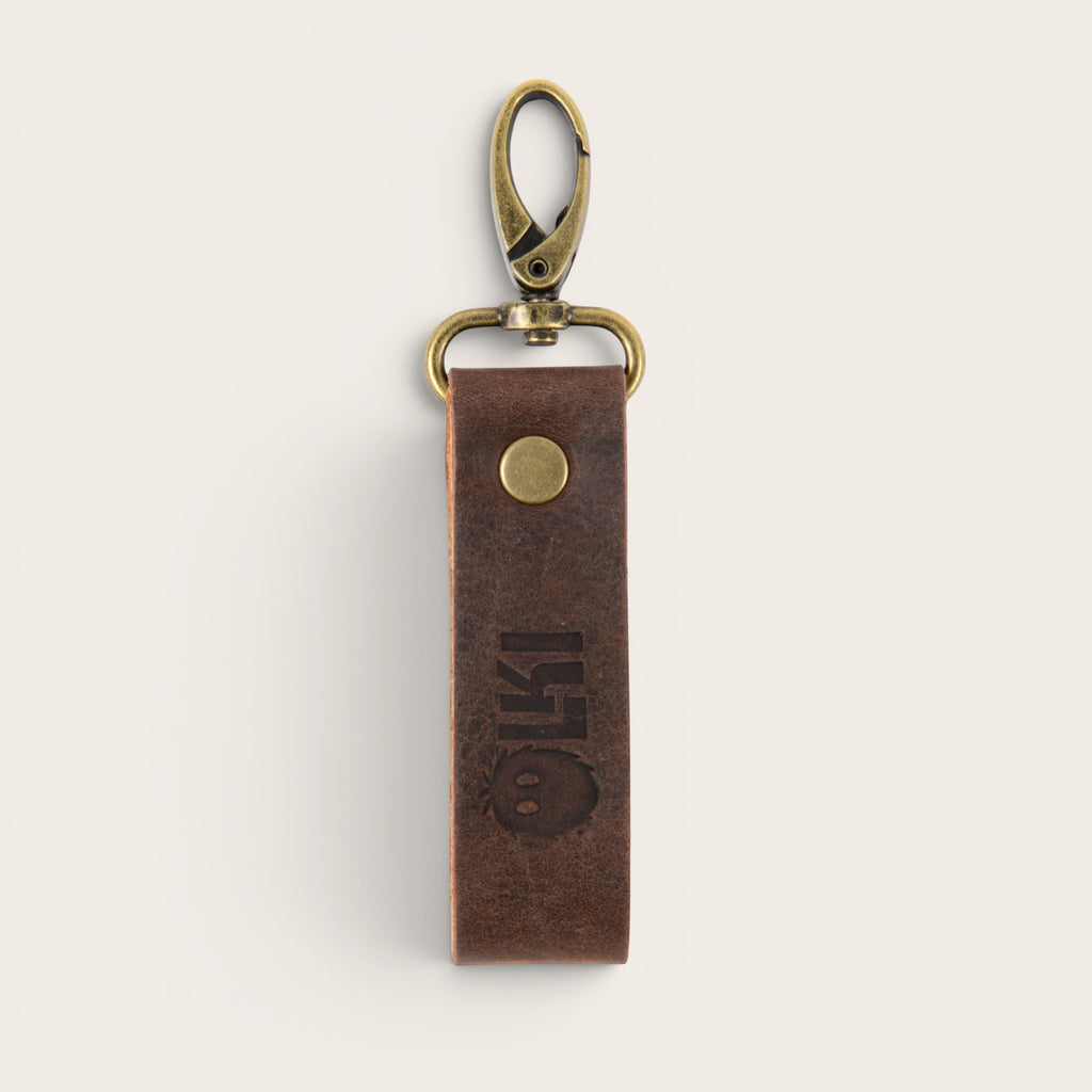 Llavero OLKI Huilo Huilo de cuero marrón oscuro con mosquetón metálico envejecido y logo grabado.