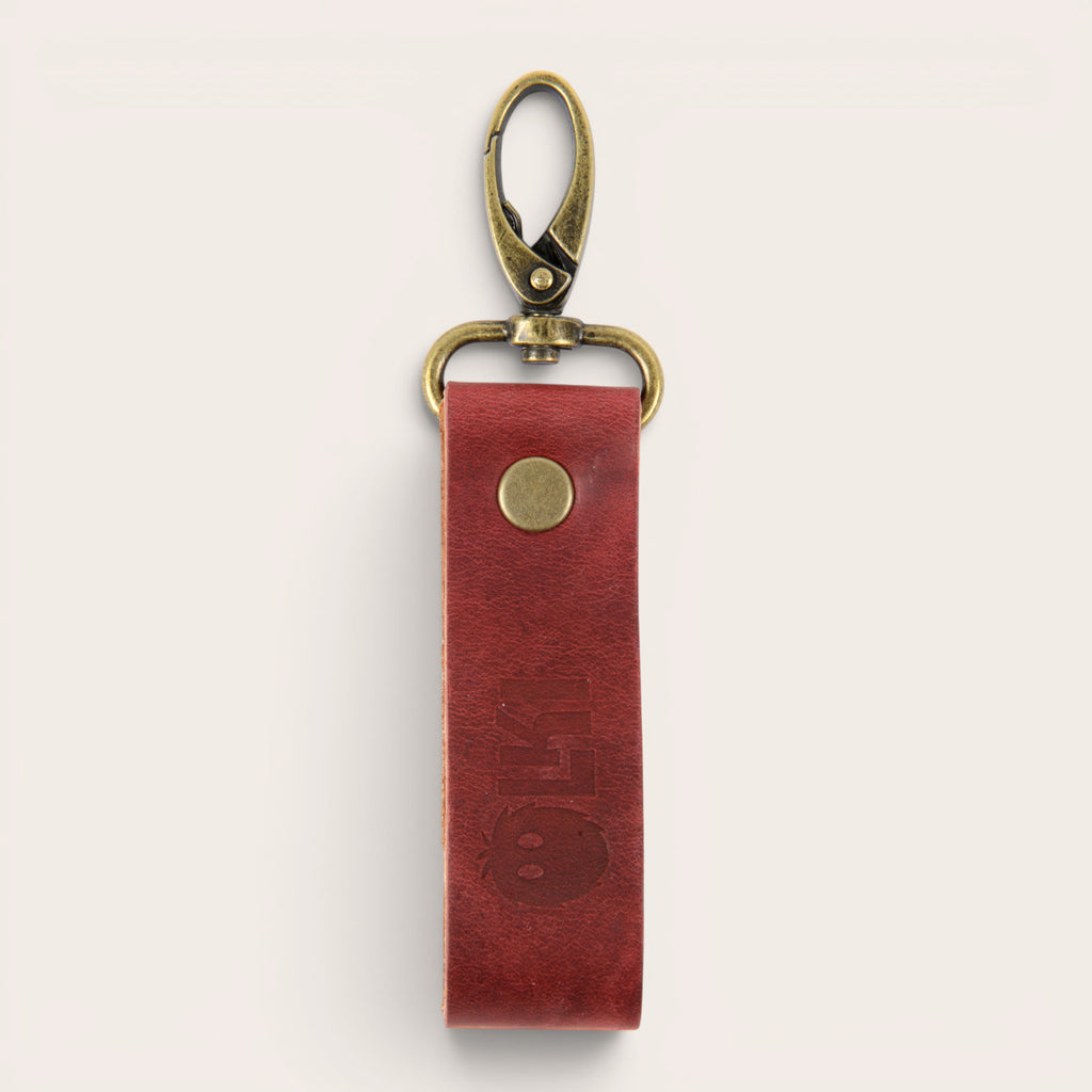 Llavero OLKI de cuero rojo con mosquetón vintage y detalle de logo grabado. Diseño funcional y elegante.