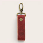 Llavero OLKI de cuero rojo con mosquetón vintage y detalle de logo grabado. Diseño funcional y elegante.