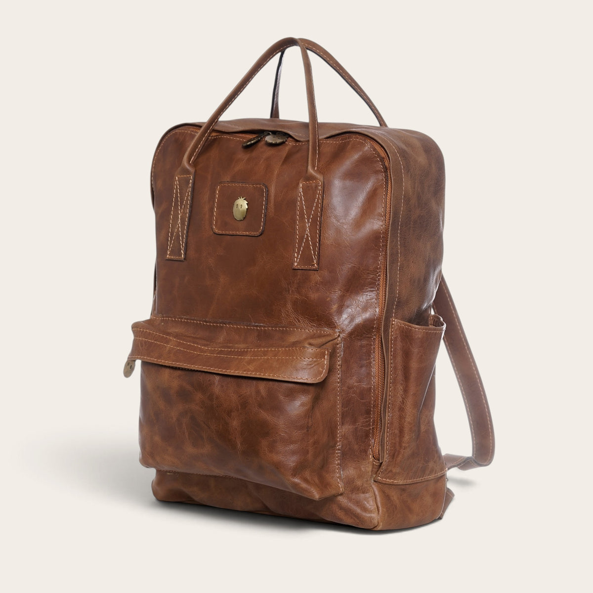 Mochila OLKI Caliboro de cuero natural color café con diseño compacto, bolsillo frontal y asas superiores
