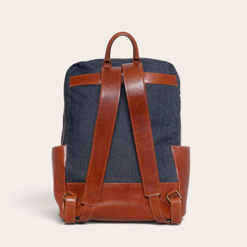 Mochila OLKI Imperial de mezclilla azul con correas y detalles en cuero marrón, vista trasera estructurada.