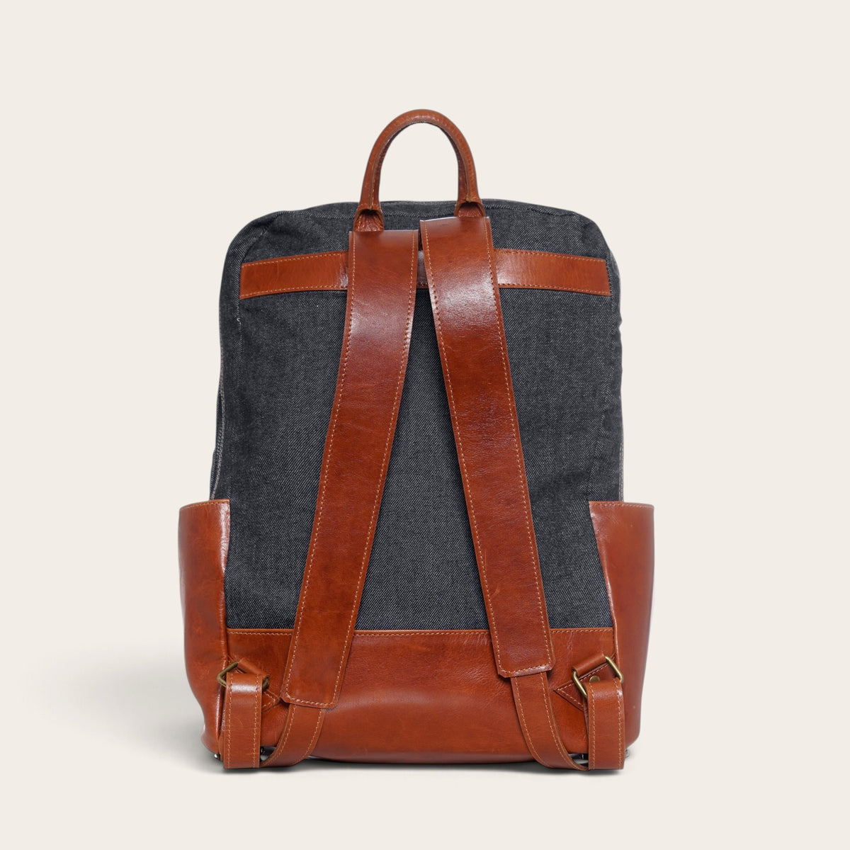 Mochila OLKI Imperial de mezclilla gris con detalles y correas de cuero marrón, vista trasera estructurada.