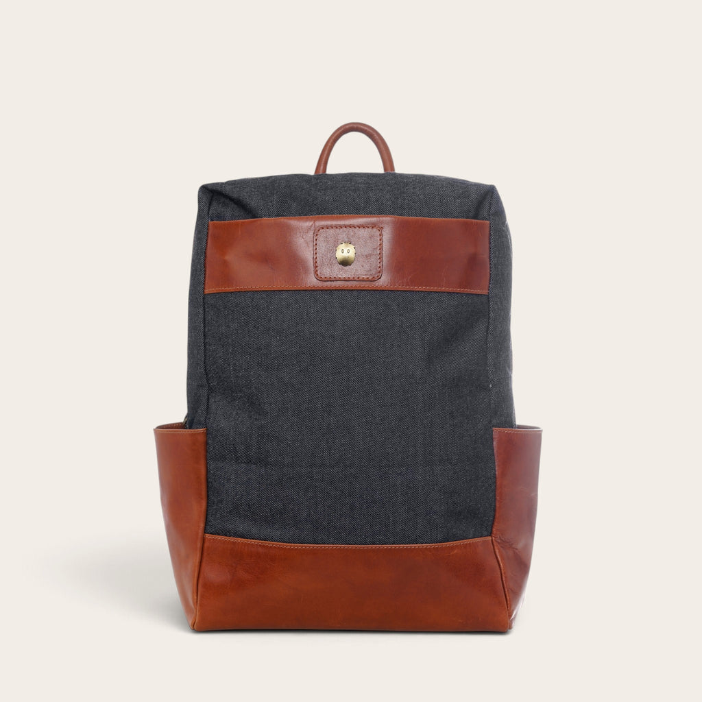 Mochila OLKI Imperial gris de mezclilla con detalles en cuero marrón, diseño estructurado y correas ajustables.