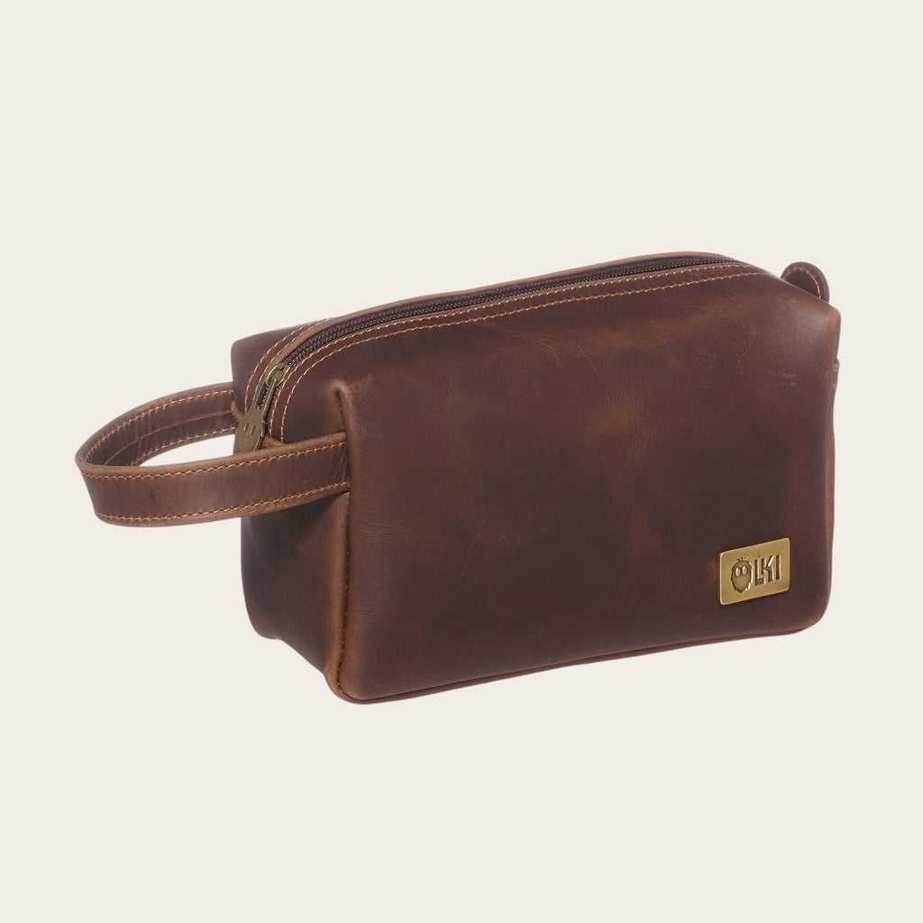 Neceser Elqui Chocolate de cuero de OLKI con asa lateral y cierre de cremallera. Ideal para viajes y uso diario.