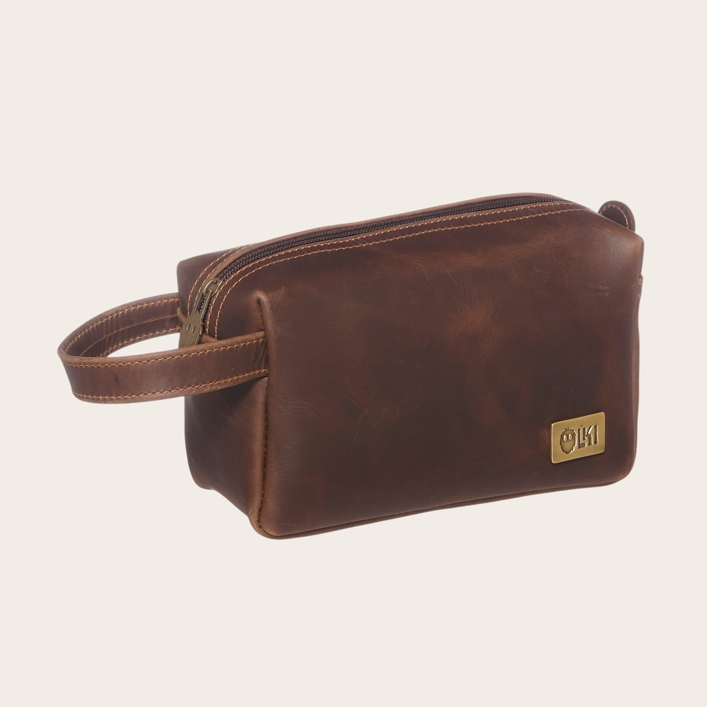 Neceser Elqui Chocolate de cuero de OLKI con asa lateral y cierre de cremallera. Ideal para viajes y uso diario.