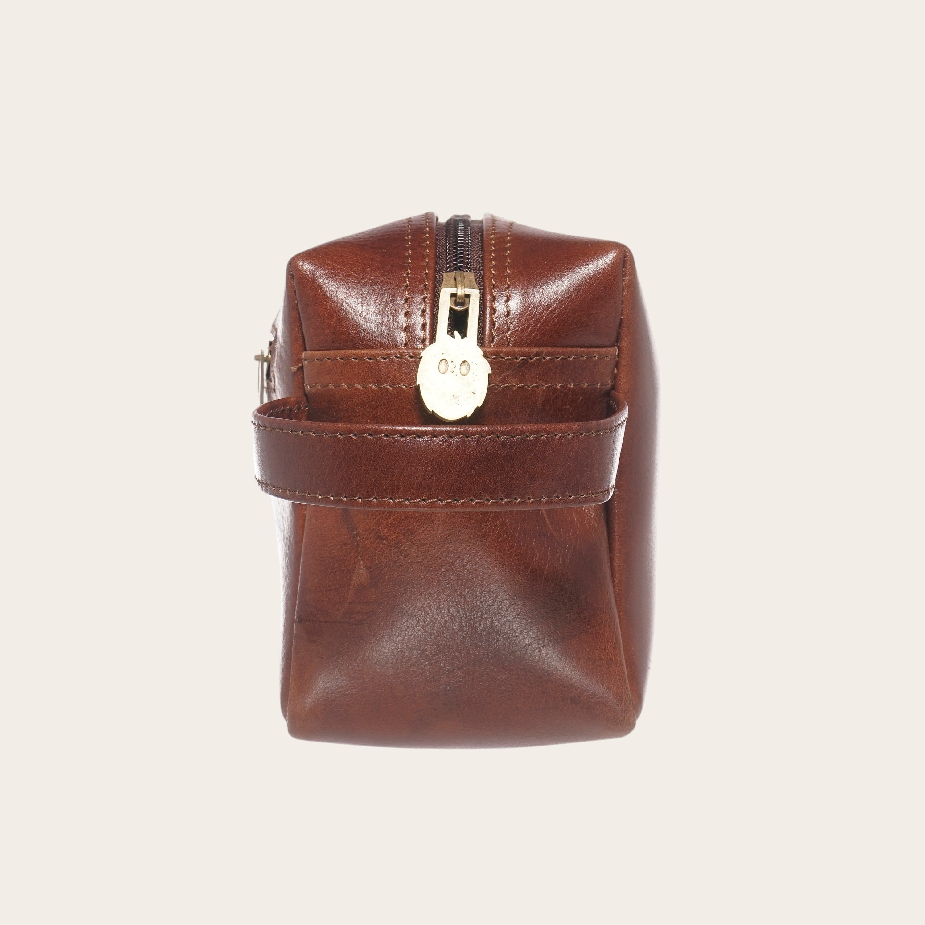 Neceser Elqui Castaño de OLKI en piel marrón con cremallera dorada y asa lateral. Ideal para viajes.